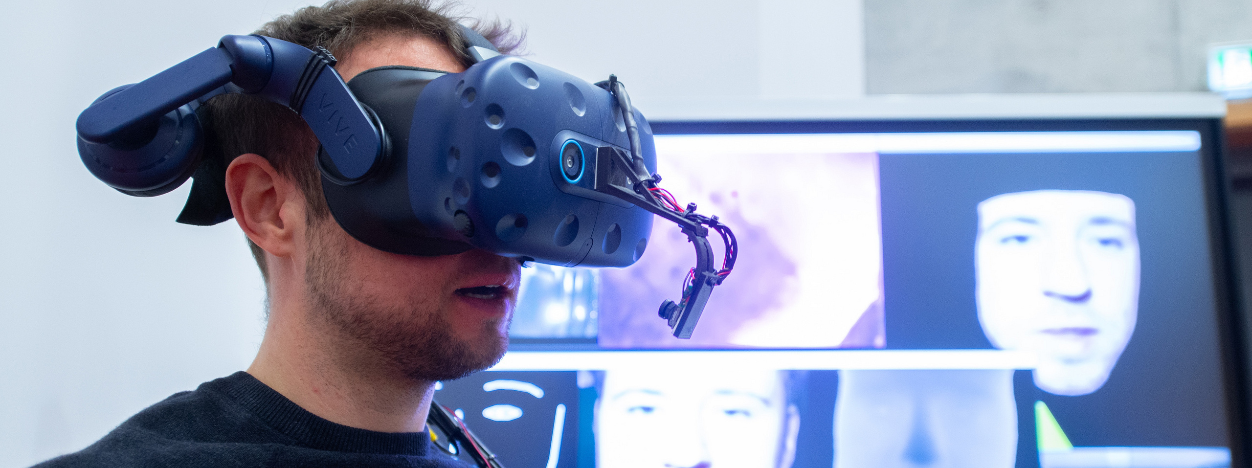 Mann mit Virtual-Reality-Brille vor einem Monitor
