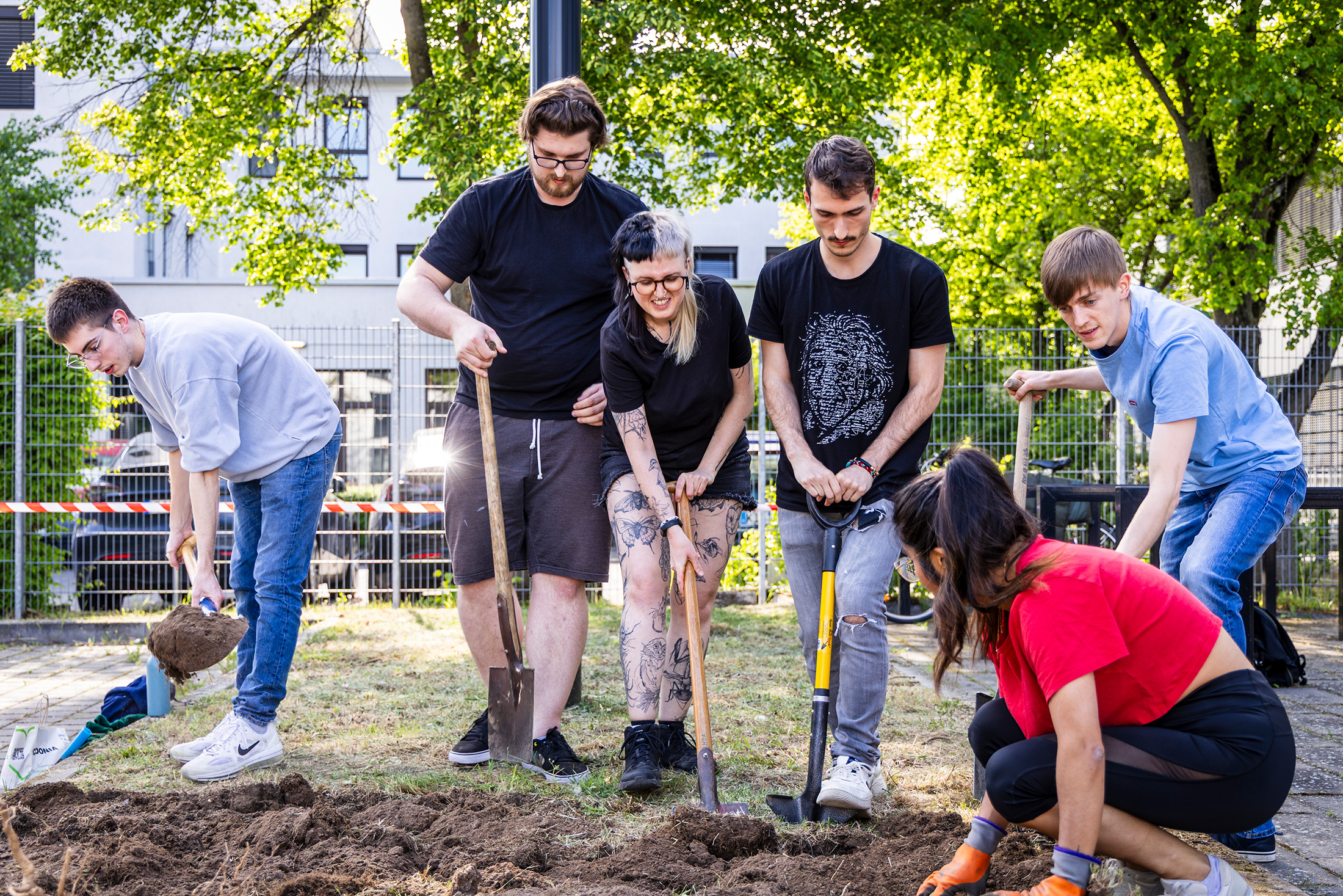 Gruppe von Studierenden graben mit Spaten in einem Beet