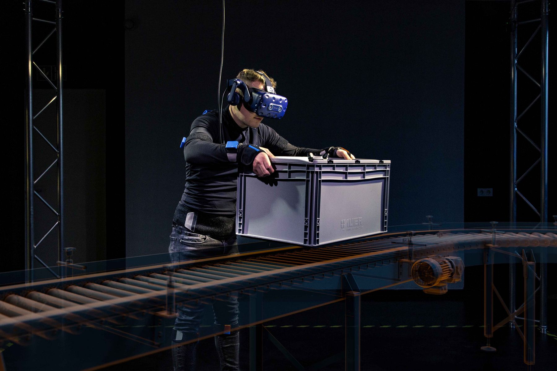 A student wearing virtual reality glasses putting a box on a model assembly line