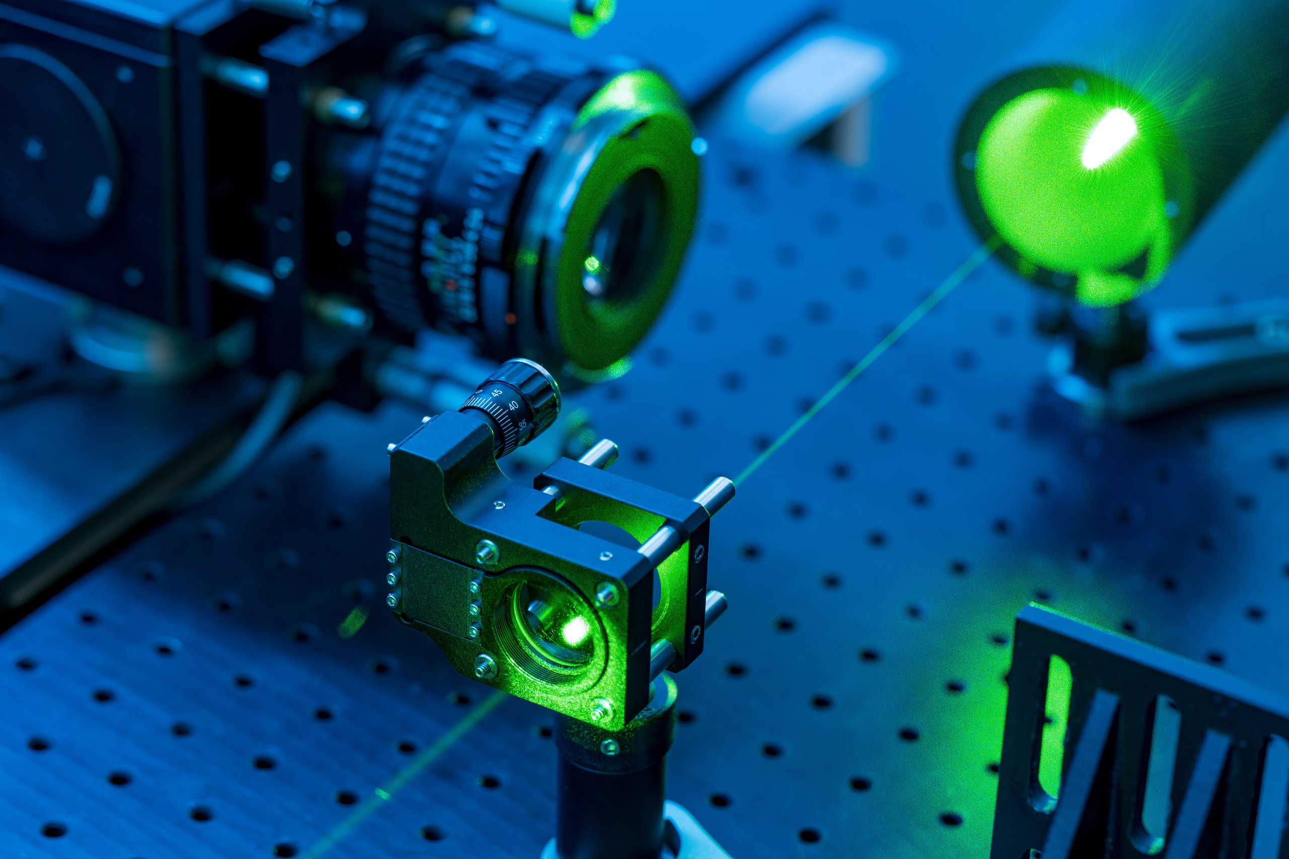 Laborgeräte zur Lasermesstechnik in grünes und blaues Licht getaucht