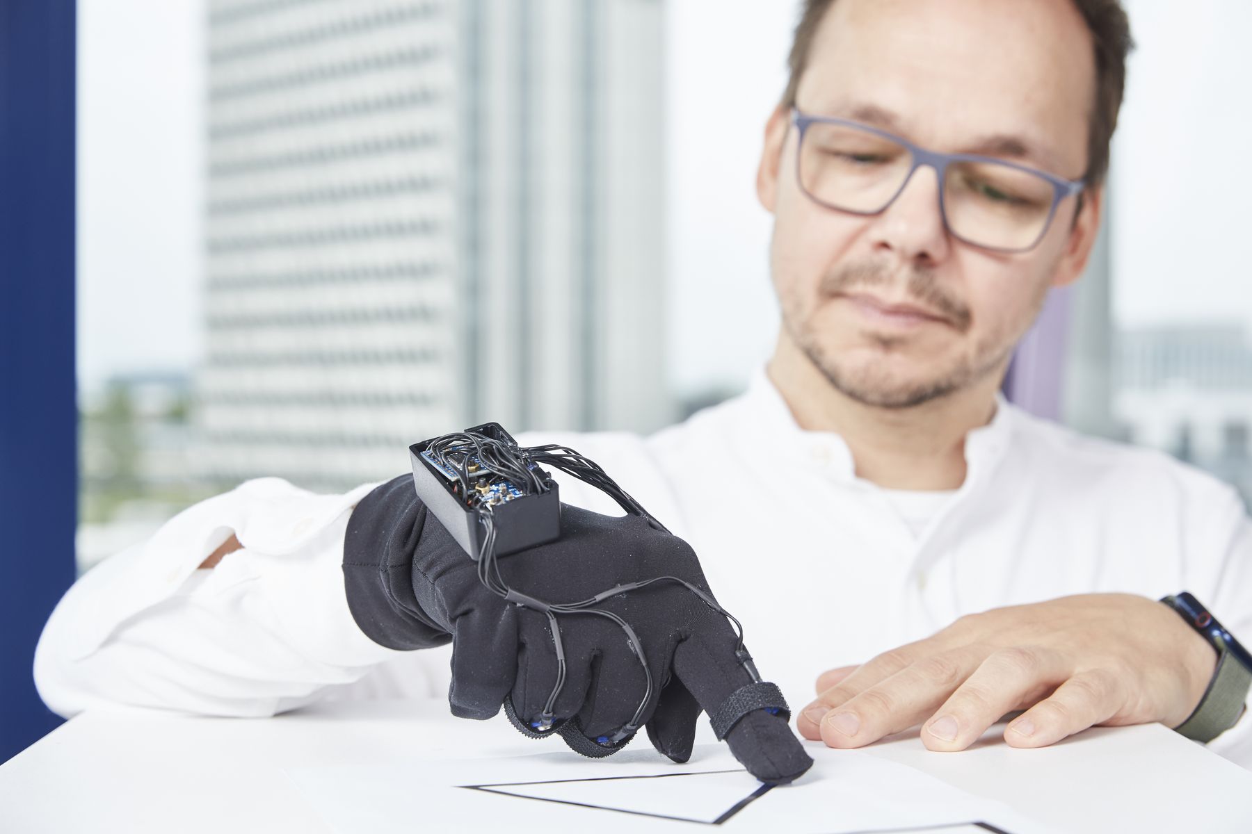 Prof. Carsten Zahout-Heil fährt mit dem schwarzen Sensor-Handschuh über eine Zeichnung. 