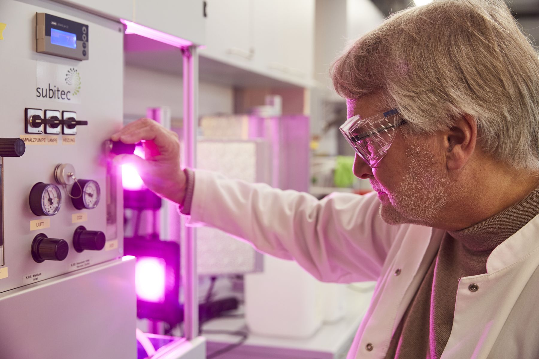Prof. Pollet taking a close look at a smaller reactor bathed in purple light
