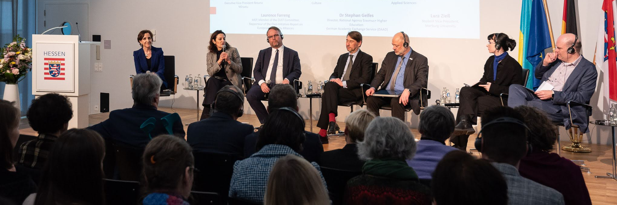 Panel mit sieben Teilnehmenden auf dem Podium