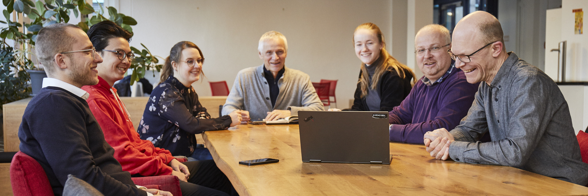 Team members of the Student Project Office for Transport and Mobility (SPV) hold a meeting around a long wooden table with a laptop.