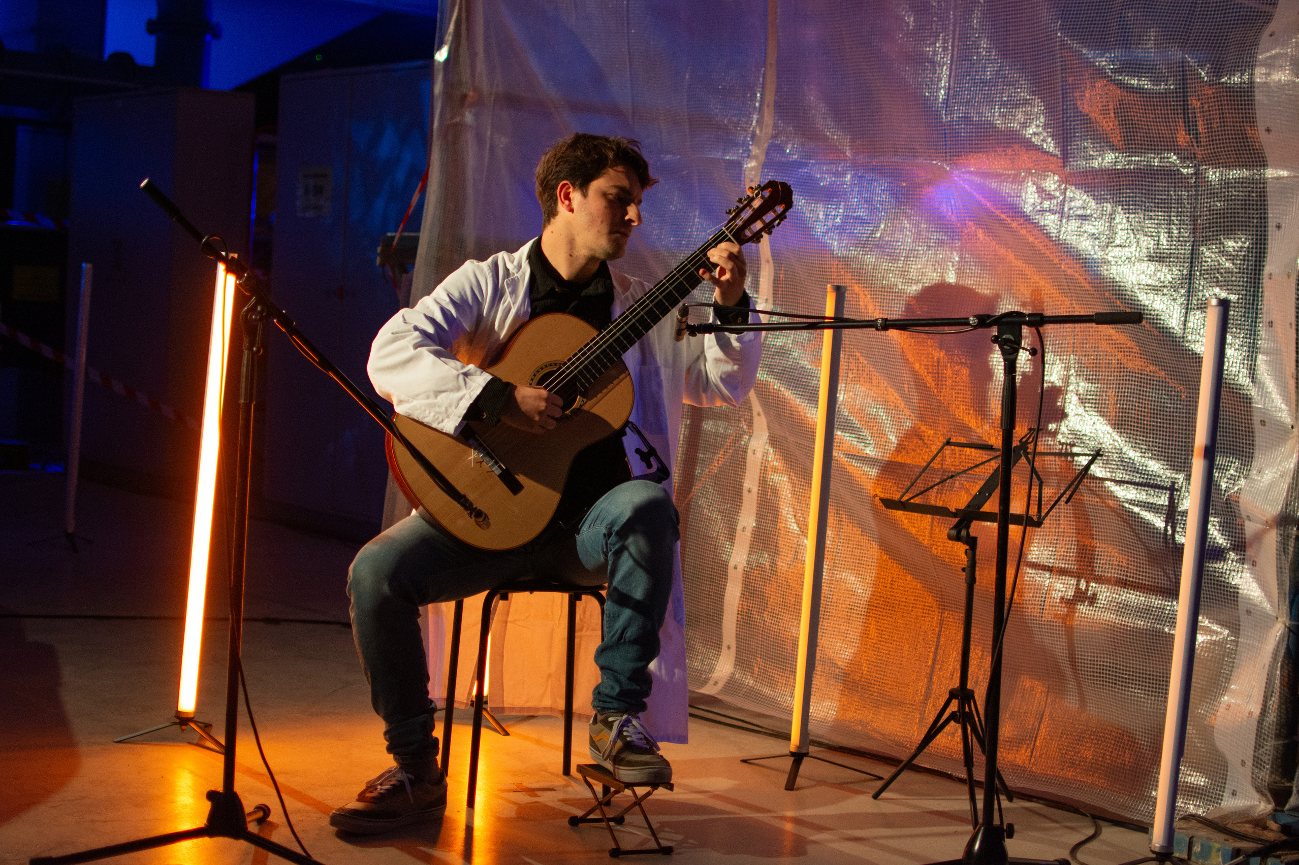 Gitarrist im Sitzen auf bunt beleuchteter Konzertfläche