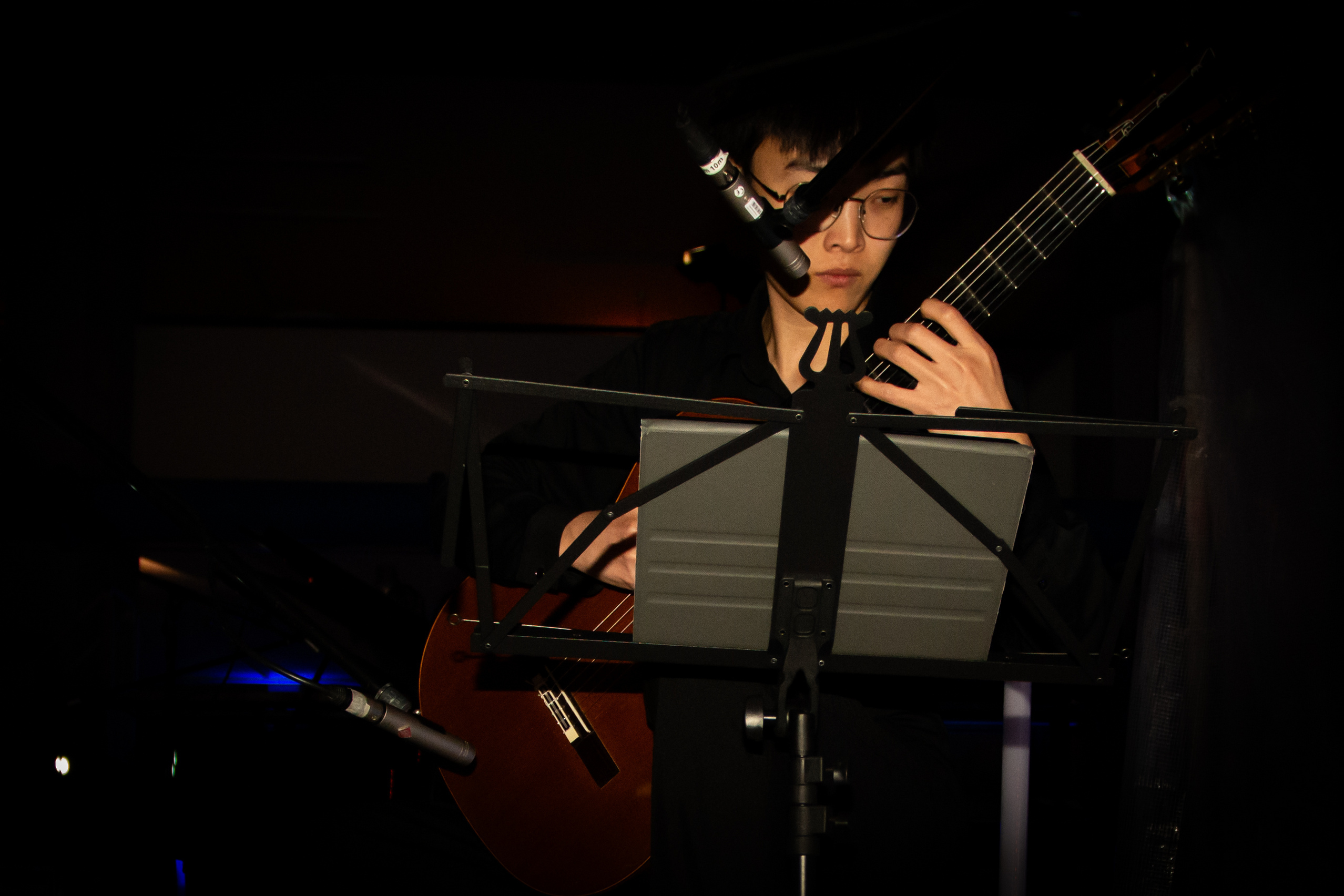 Gitarrist sitzend vor dunklem Hintergrund