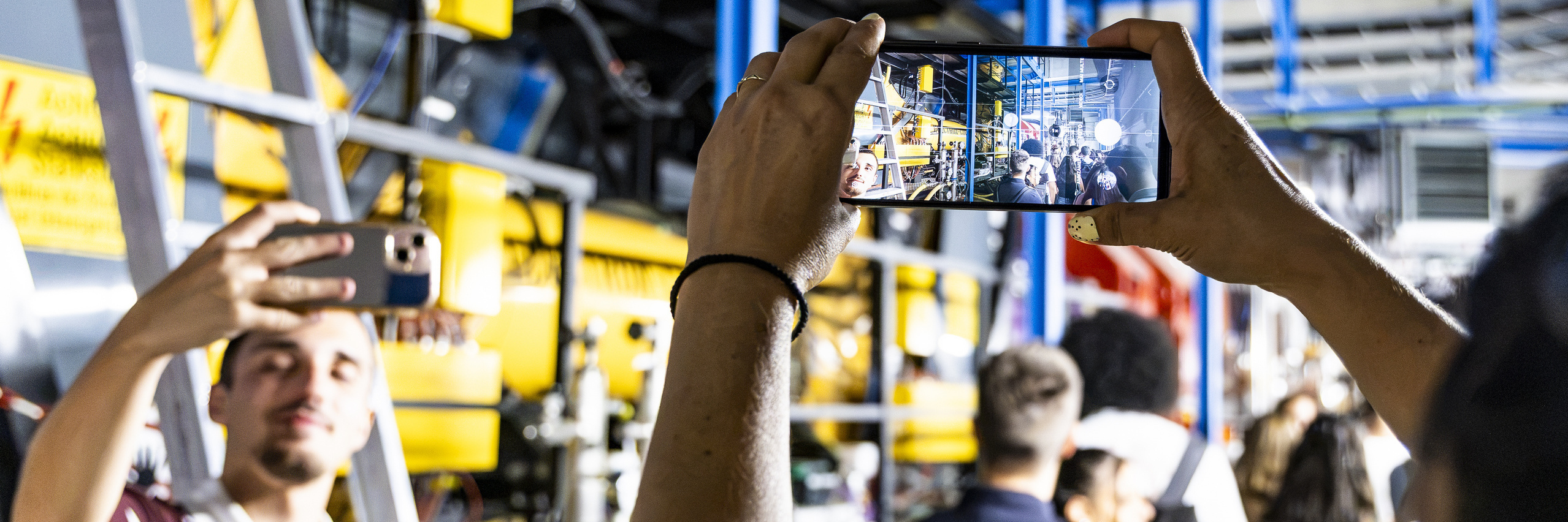 Studierende machen Fotos in einer großen Laborhalle