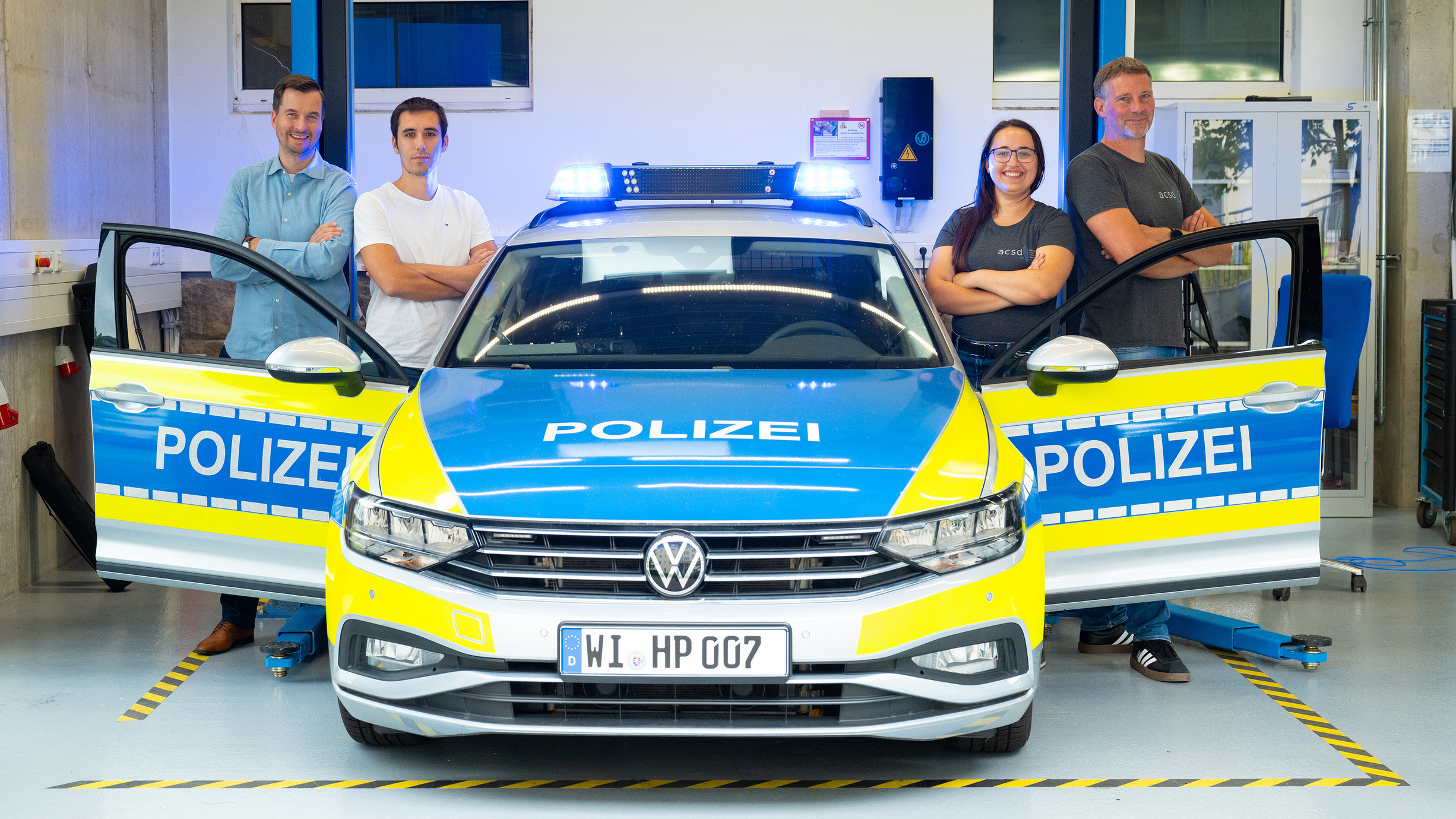 Team des HECA-Projekts steht um ein Polizeiauto herum