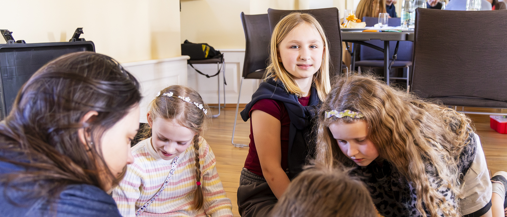 Kinder knien im Rathausaal auf dem Boden und zeichnen und beschreiben ihre Entwürfe für den Platz der Kinderrechte. 