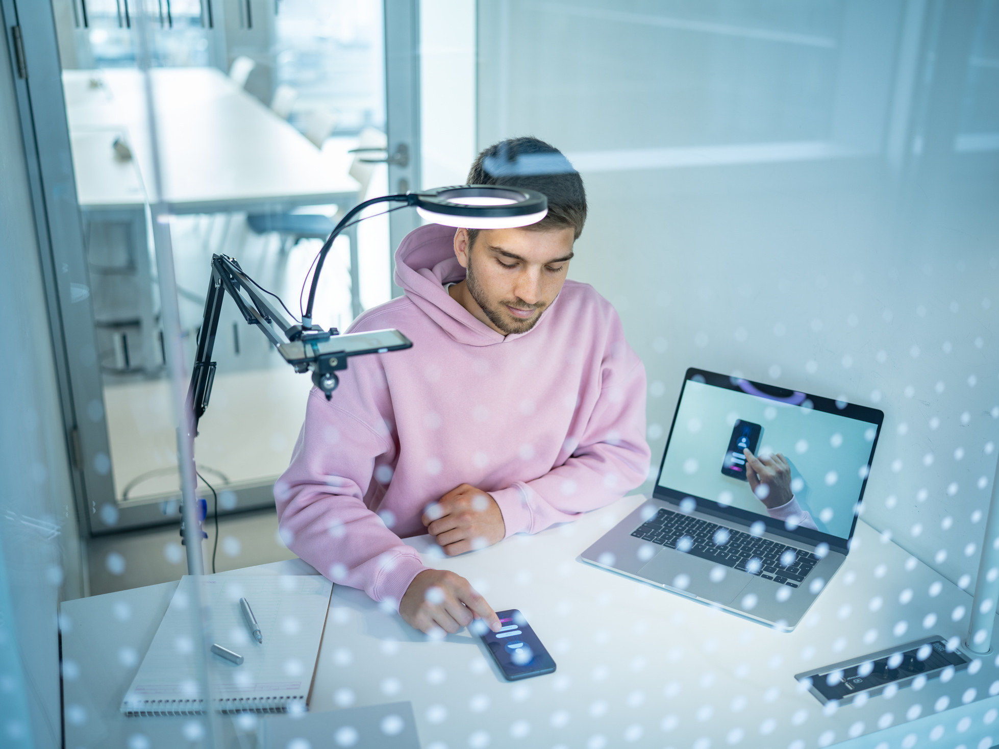 Young man in a test setup with mobile phone, laptop and overhead camera