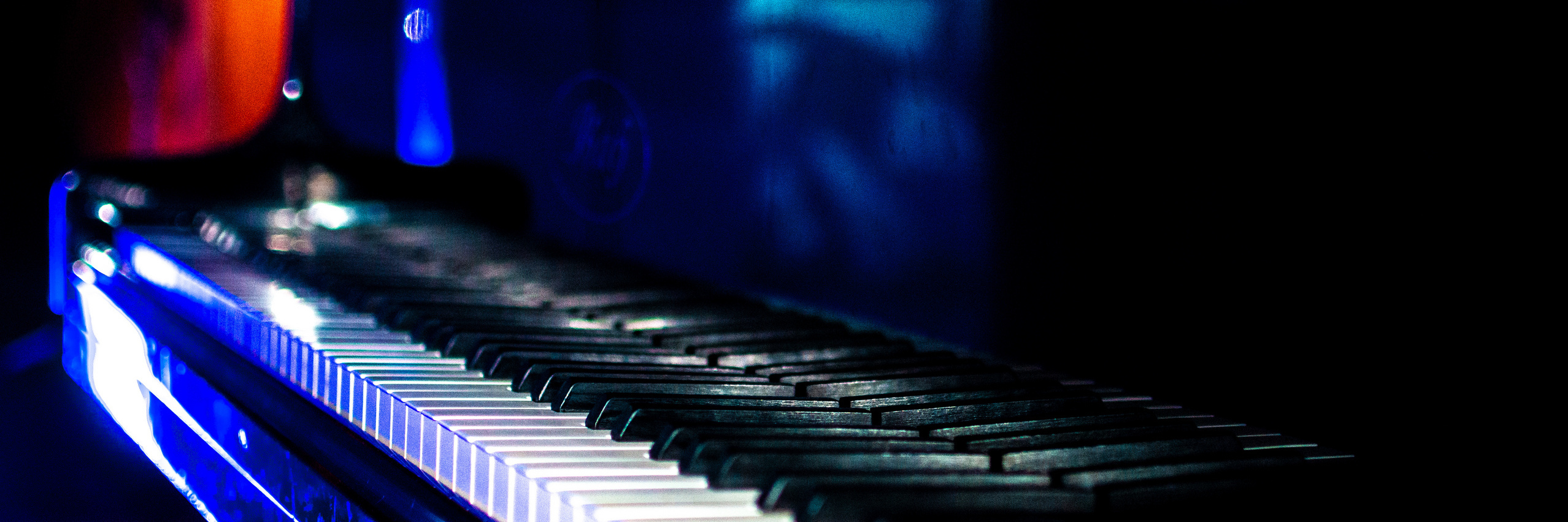 Bunt beleuchtete Tastatur eines Flügels vor dunklem Hintergrund