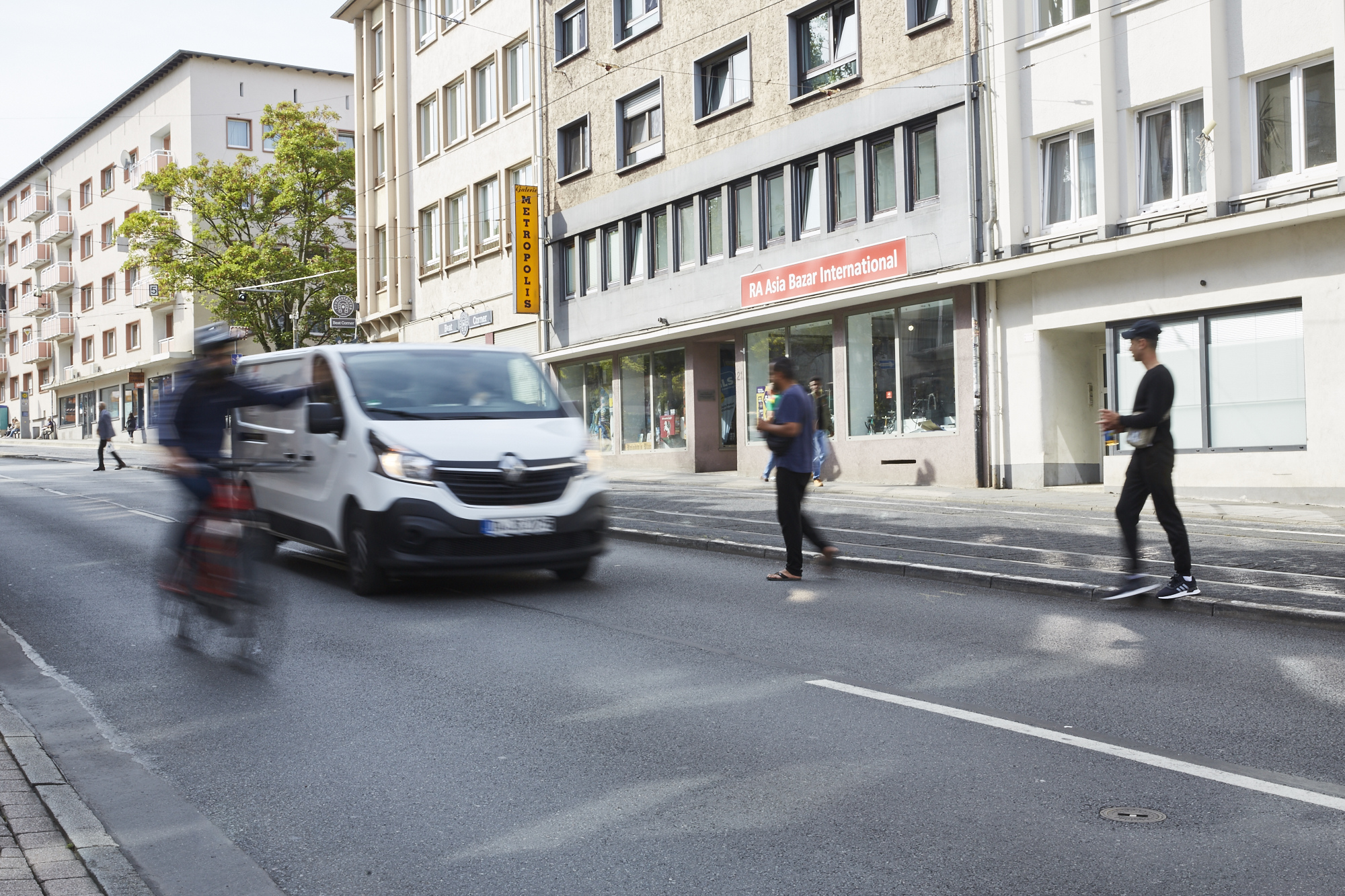 Verkehrsszene mit Auto, Radfahrer und querenden Fußgängern am Cityring