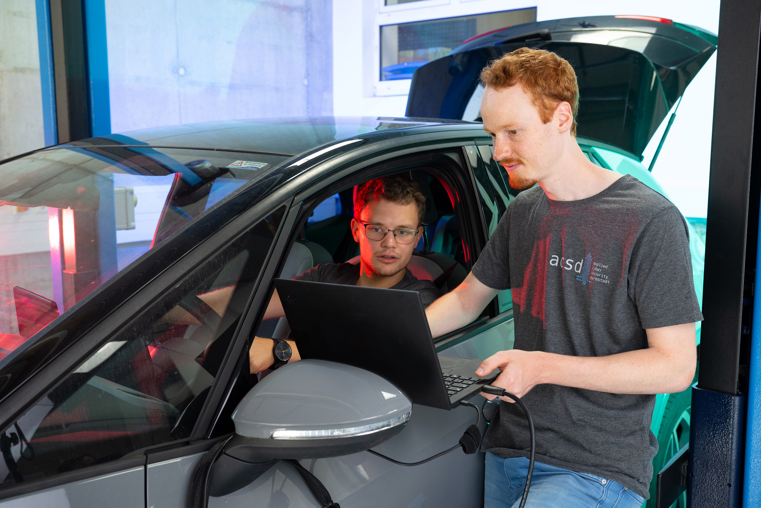 DIe beiden Doktoranden diskutieren und arbeiten am E-Auto. 