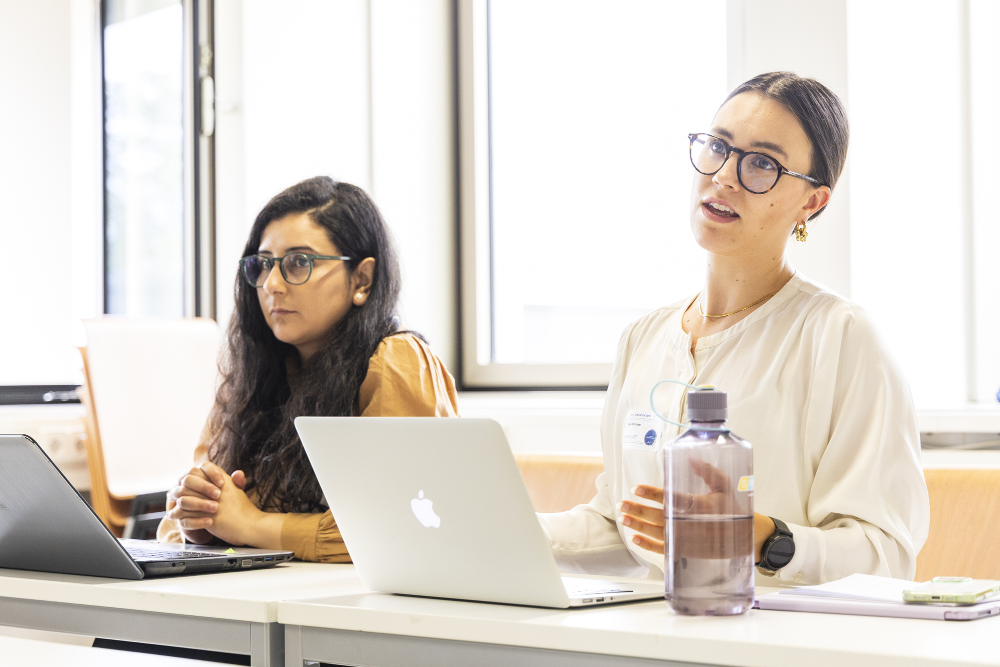 Zwei Studentinnen, an einem Tisch sitzend, bei der ARbeit