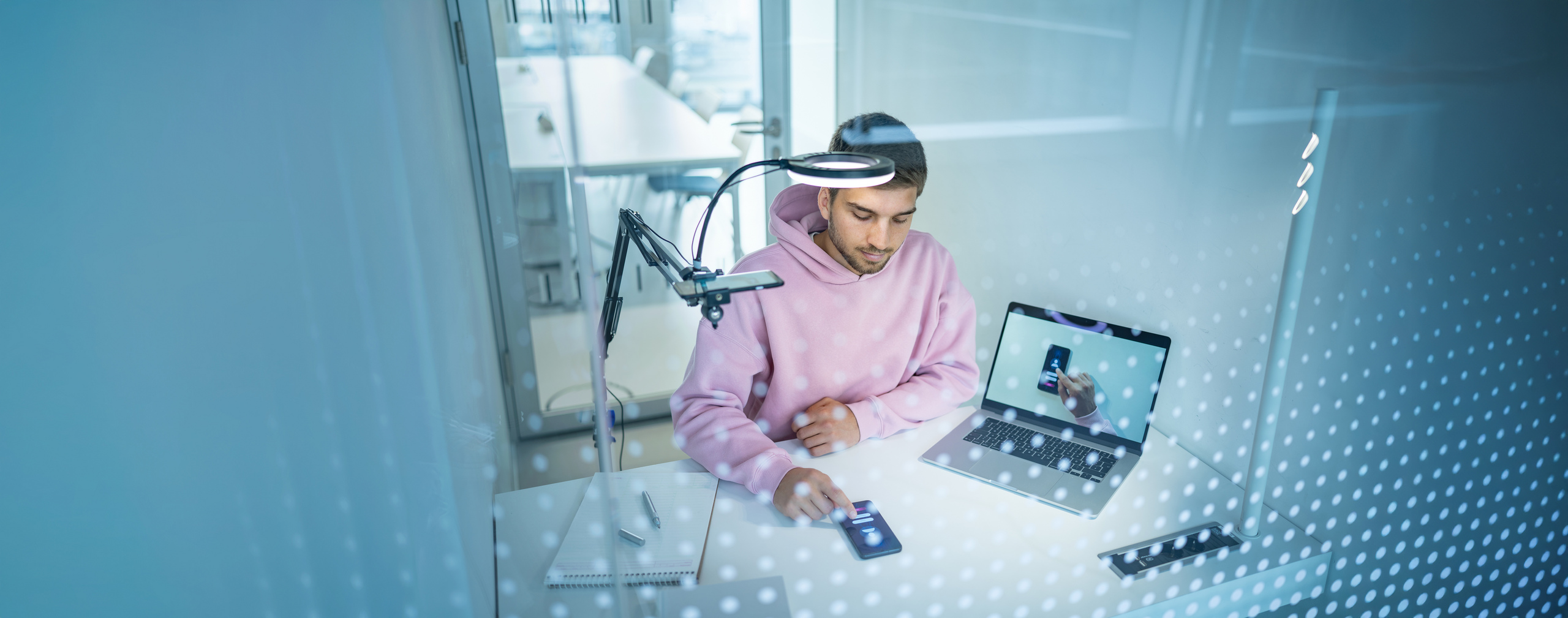 Junger Mann in einem Versuchts-Setup im USP-Lab mit Handy, Bildschirm und Overhead-Kamera