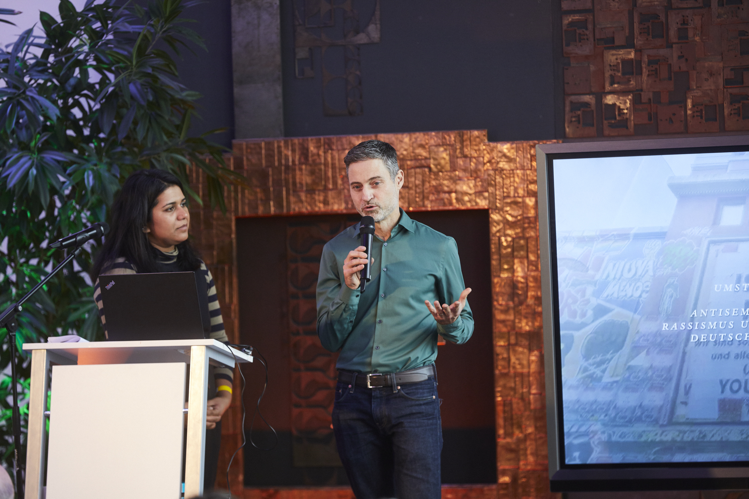 Meron Mendel und Saba-Nur Cheema stehen auf dem Podium