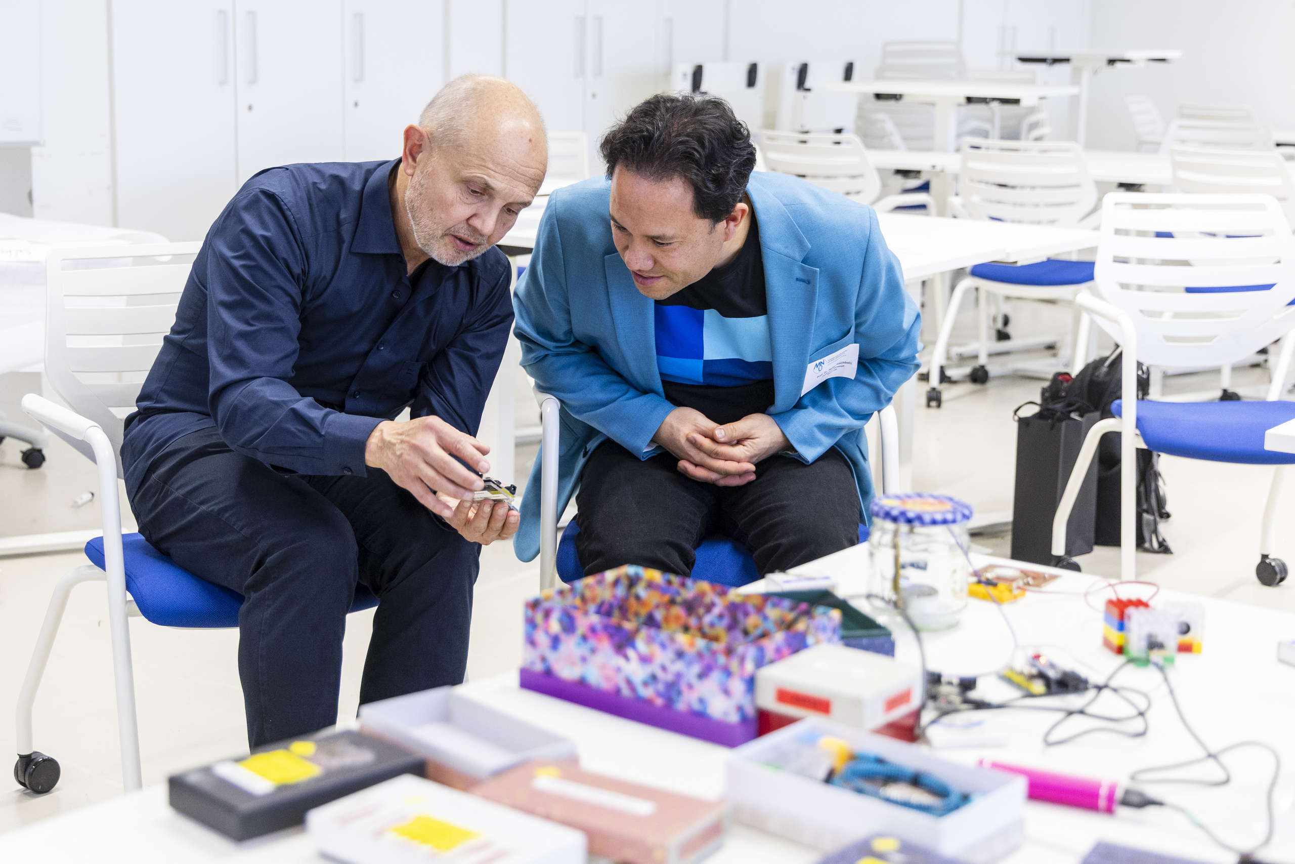 Torsten-Karl Strempel und Heiko Rochholz beugen sich gemeinsam über einen Versuchsaufbau.