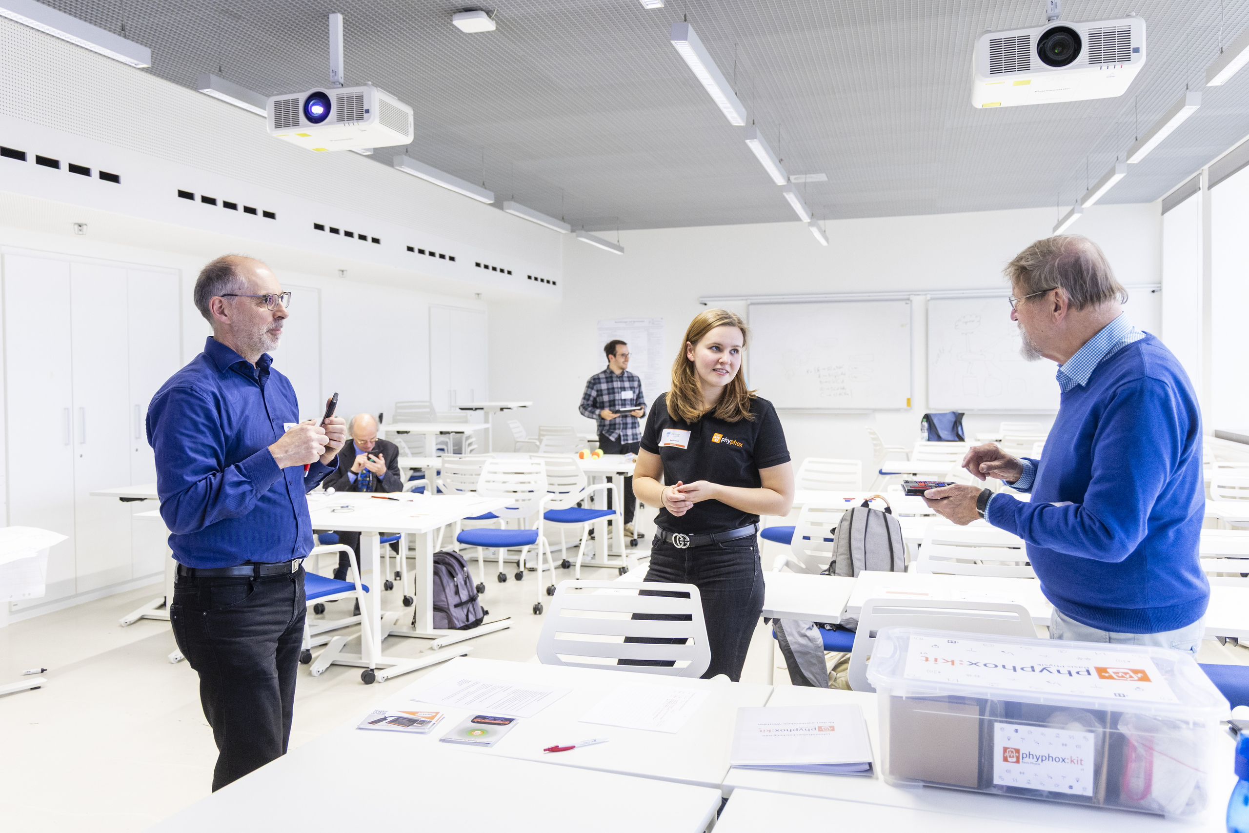 Zwei Workshop-Teilnehmer und Marija Herdt diskutieren mit Handys in der Hand. 