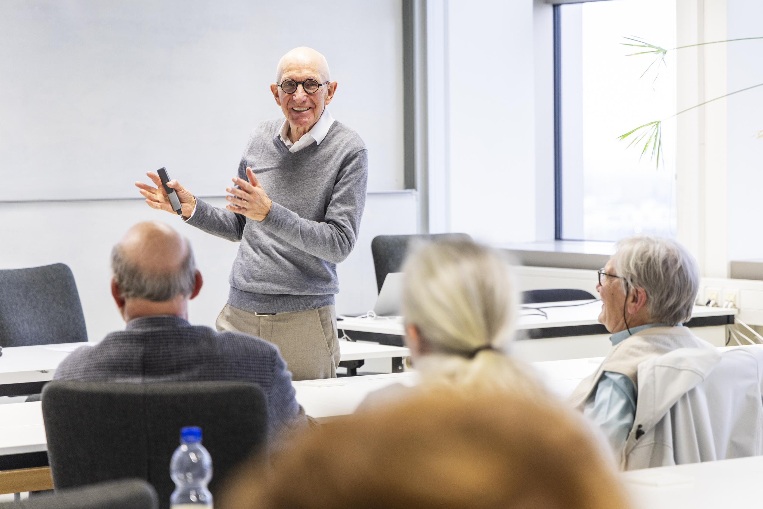 Professor Leisen steht vor einer Gruppe von Teilnehmenden, lächelt und gestikuliert.  