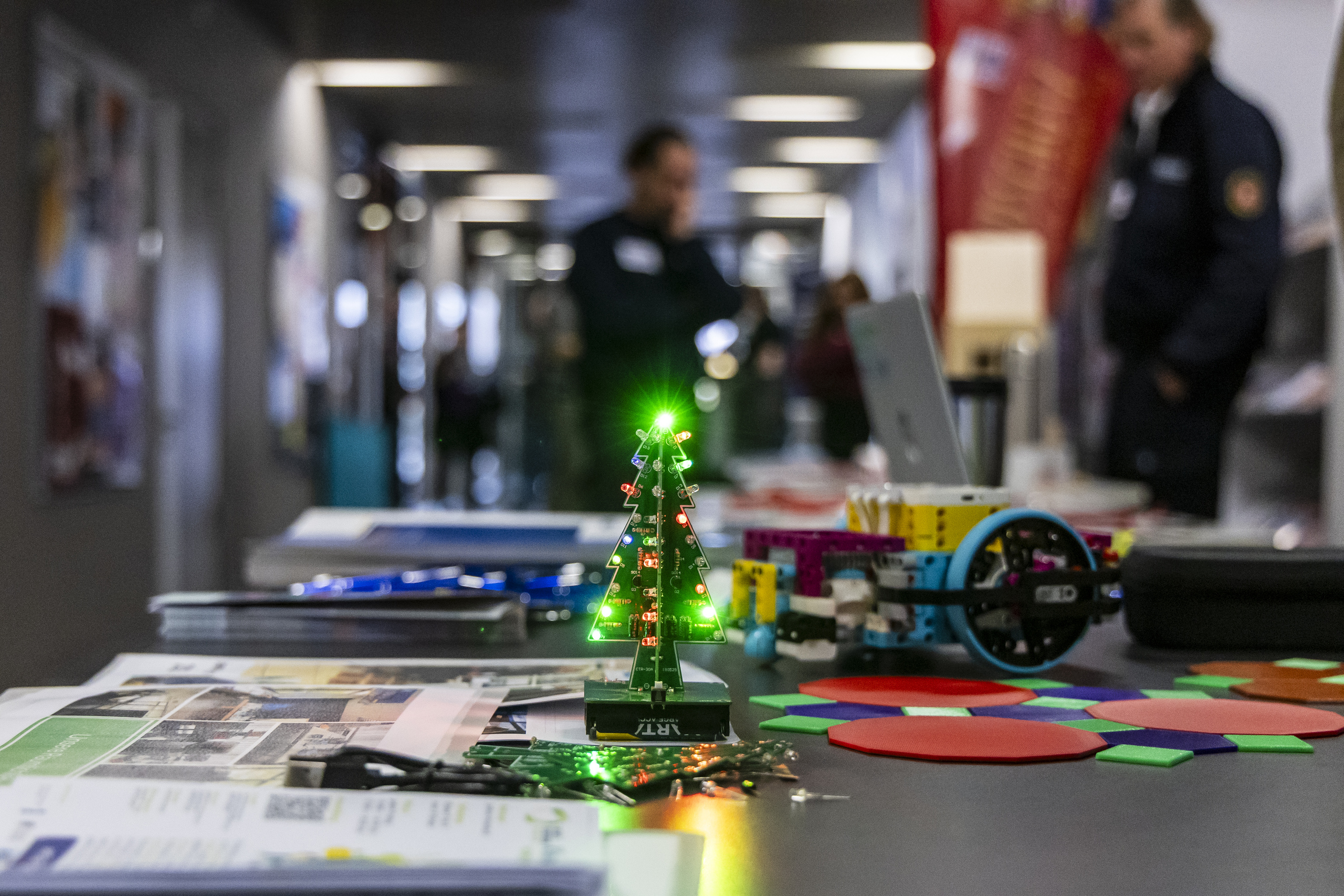 Langer Tisch mit Lernmaterialien darauf und einem kleinen leuchtenden LED-Weihnachtsbaum in der Mitte