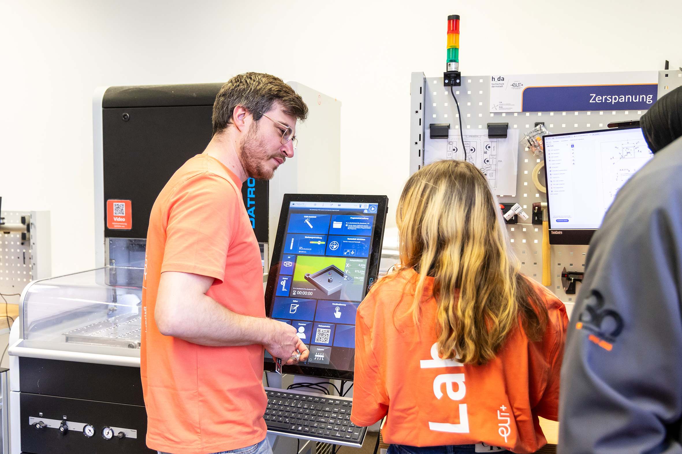 Zwei Studierende in der Diskussion vor einem Versuchsaufbau