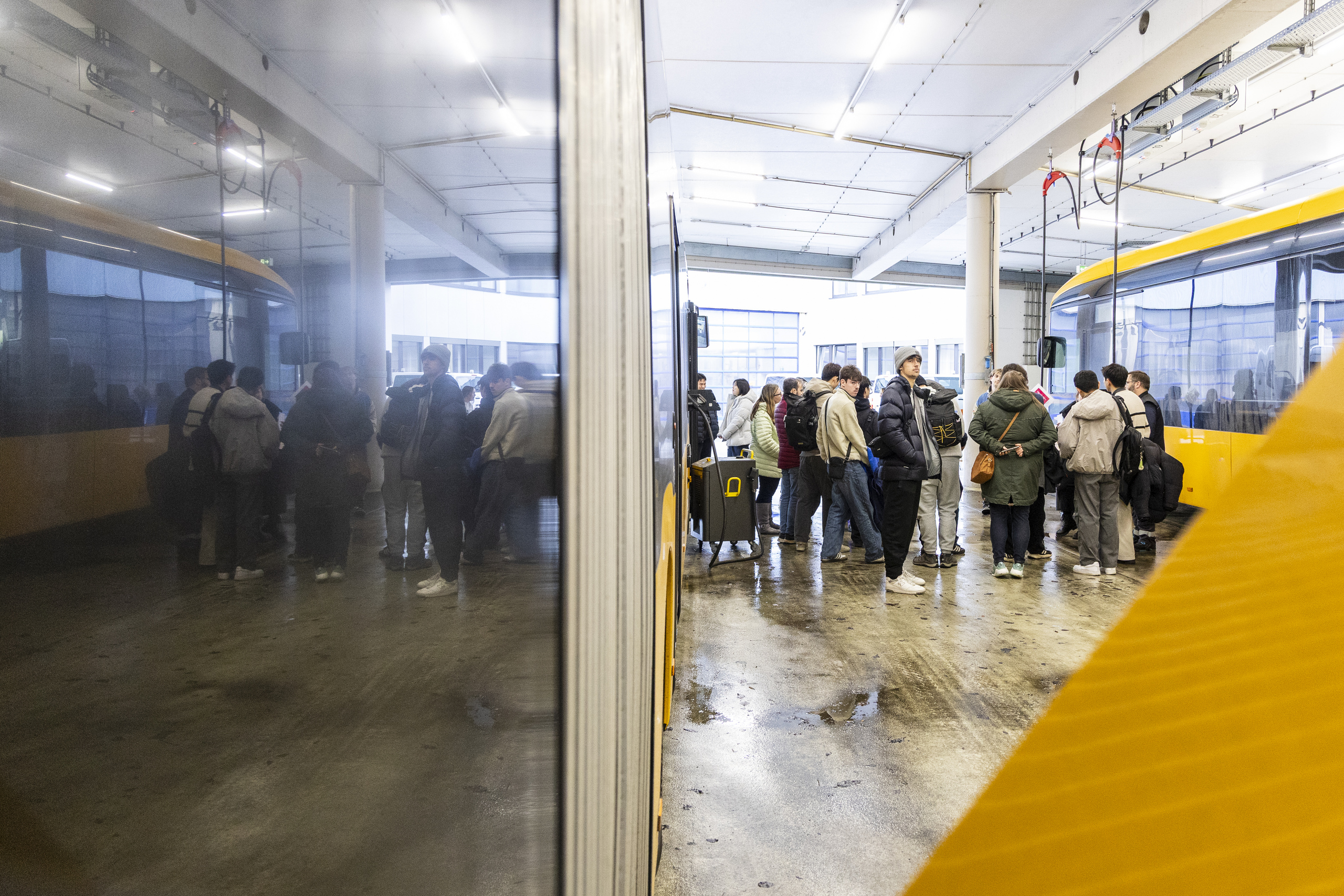 Foto der Gruppe vor einem gelben BUs mit schöner Spiegelung in einer Glasscheibe