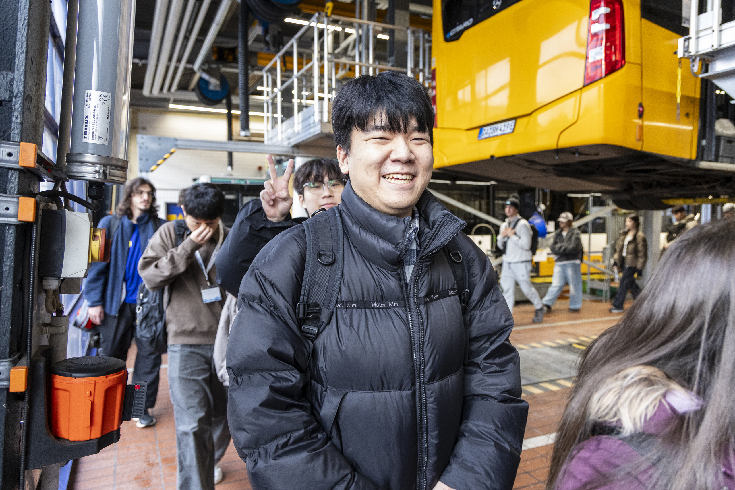 Studierender lächelt bei er Besichtigung des Bus-Depots breit in die Kamera