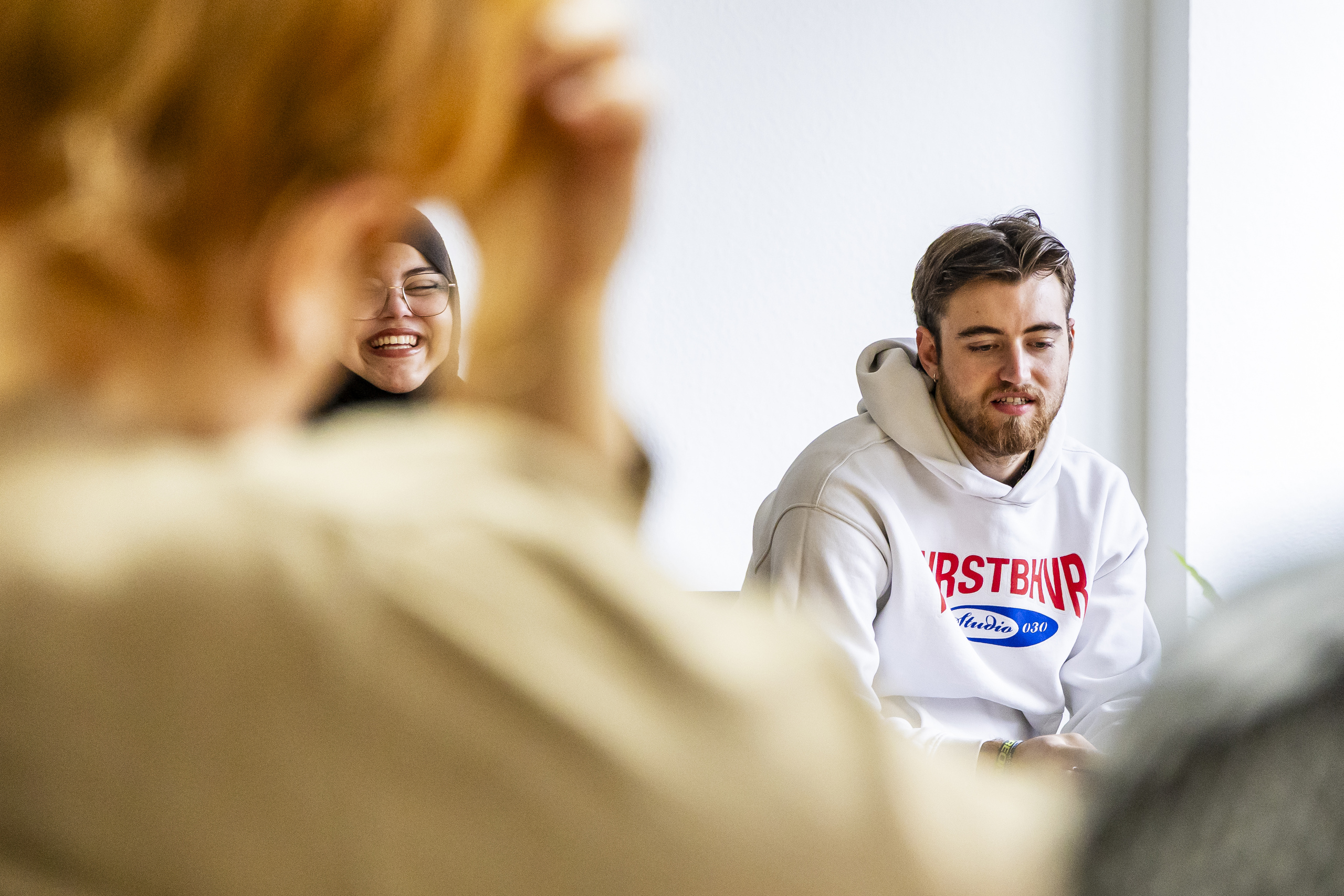 Zwei Studierende, ein junger Mann und eine junge Frau, in einer Diskussionsrunde