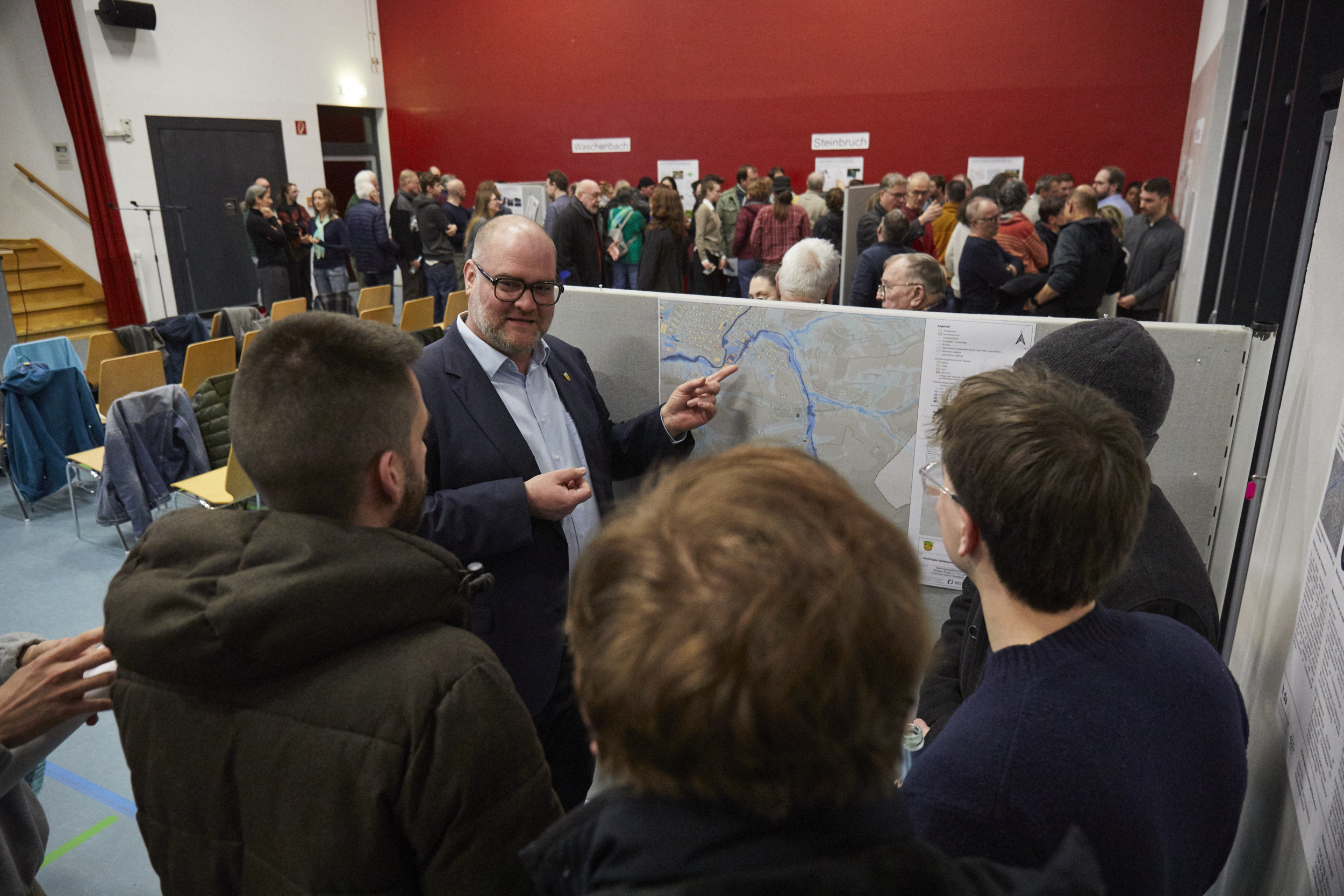 Bürgermeister vor einer Schauwand im Gespräch mit Bürger*innen