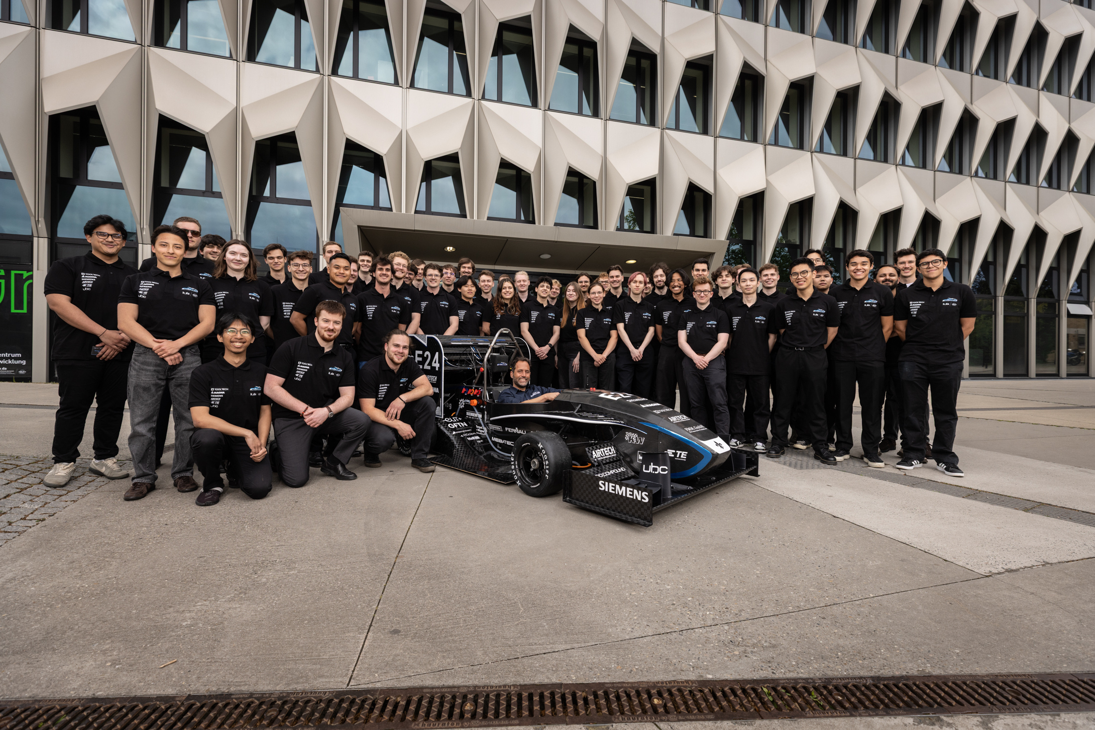 Gruppefoto FaSTDa-Team mit Rennauto vor dem h_da-Hochhaus