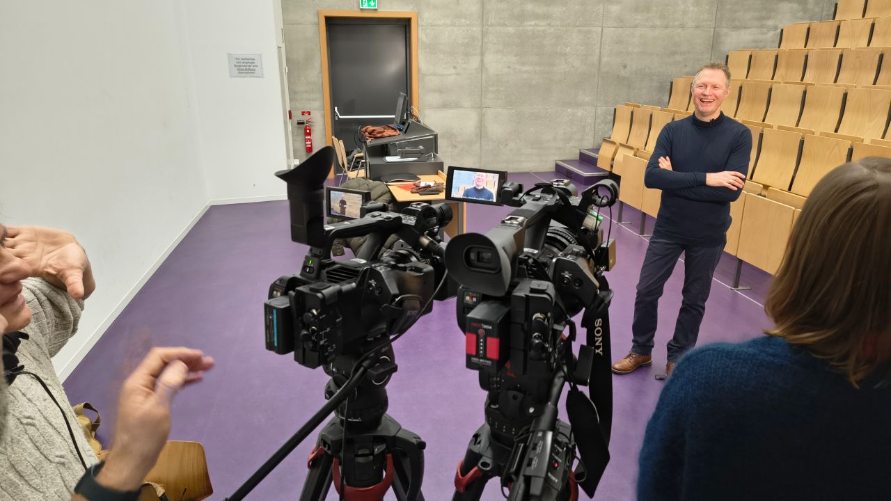 Thomas Döring steht vor Kameras in einem Hörsaal