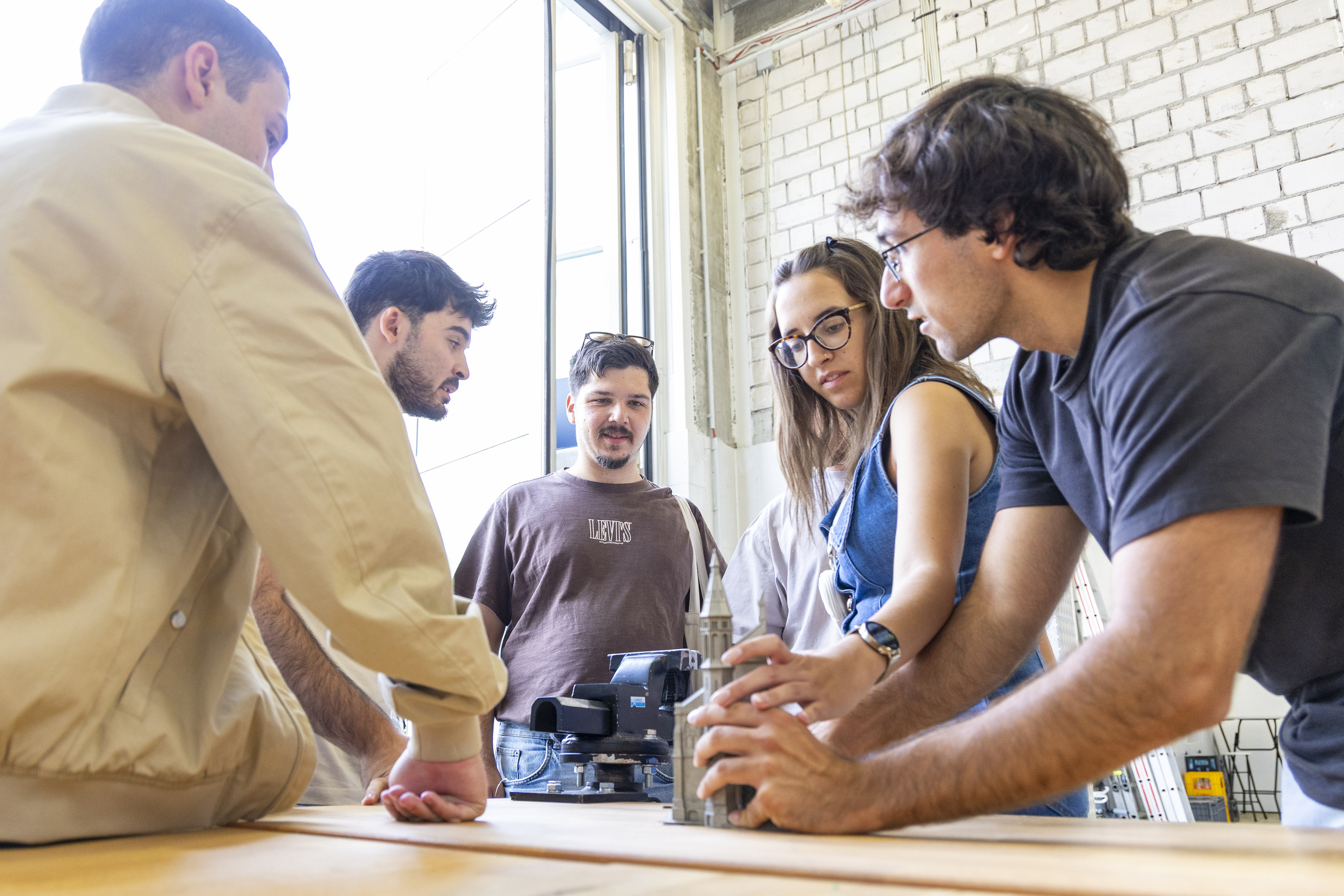 A group of students examines an architectural model 