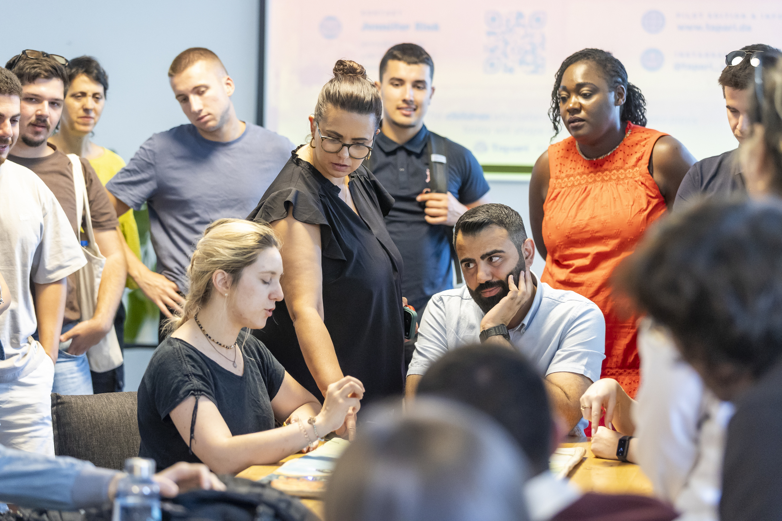 Students gather around a young entrepreneur while she explains her start-up