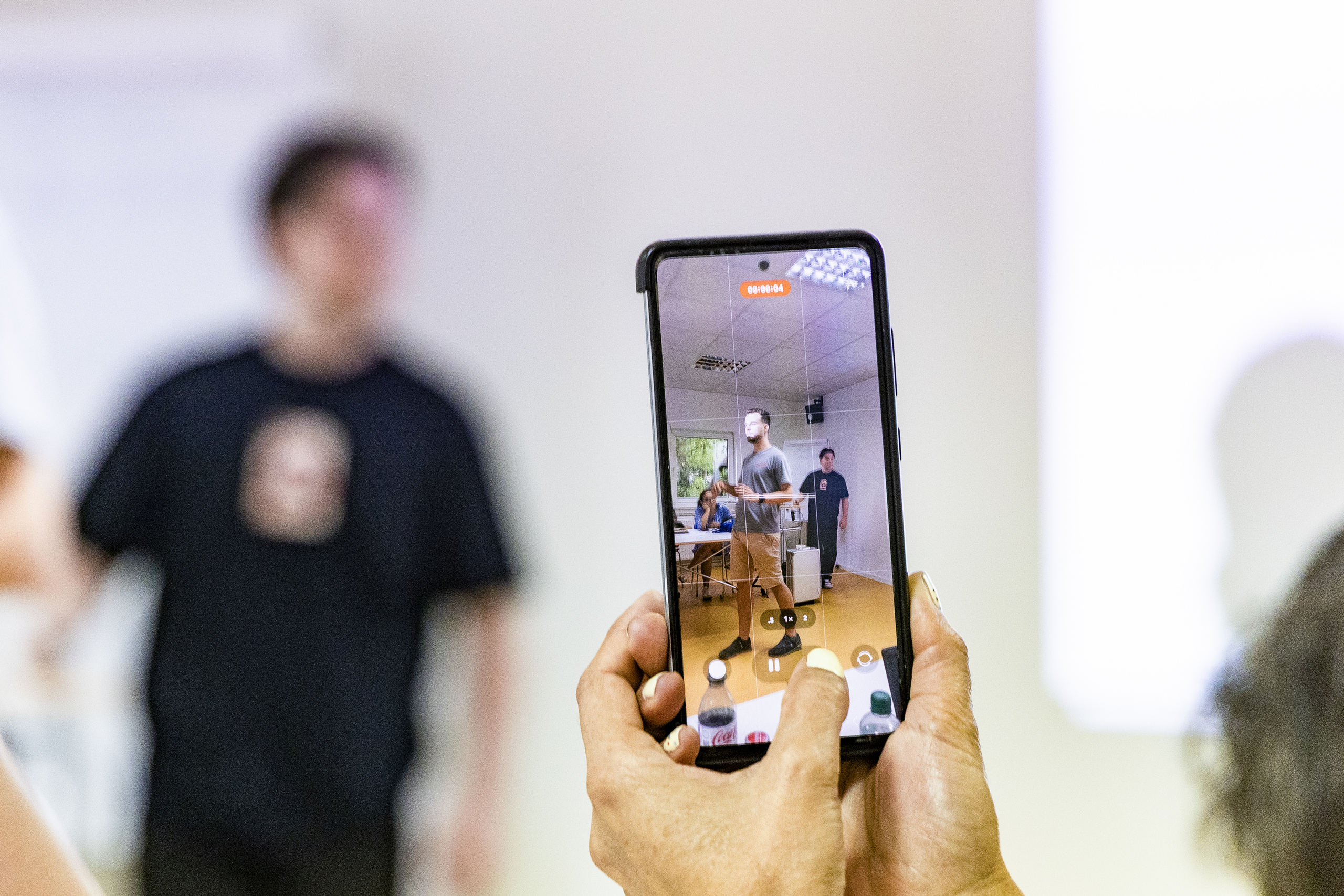 View of someone with a smartphone filming students giving their presentation